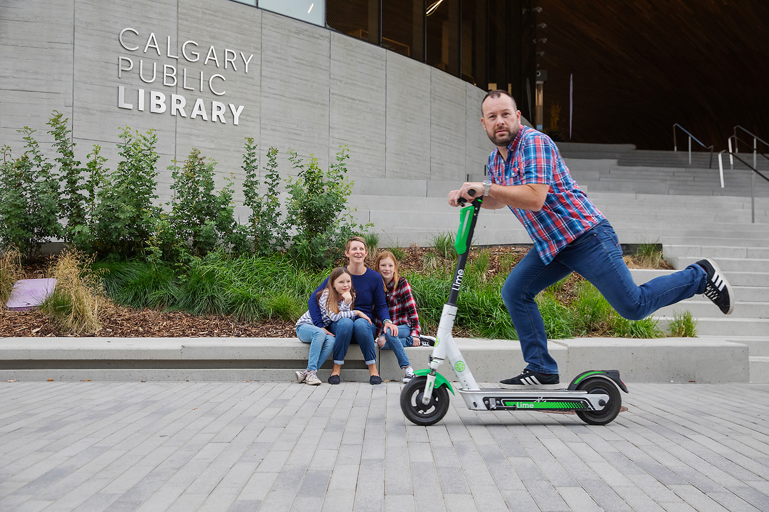 Dad using Lime Scooter near Calgary Central Public Library