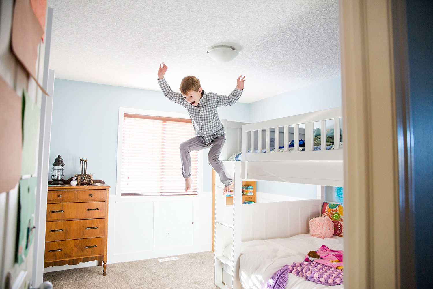 Boy jumping off of his bunk bed by lifestyle photographer, Dana Pugh