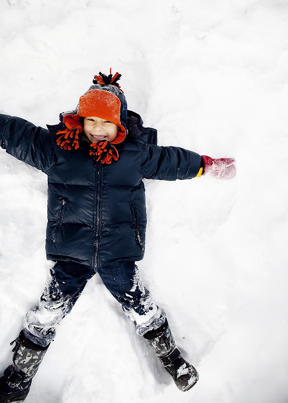 Lifestyle portrait of a boy making a snow angel