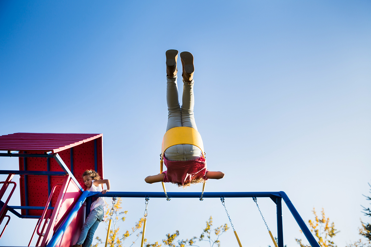 children swinging on their backyard play structure