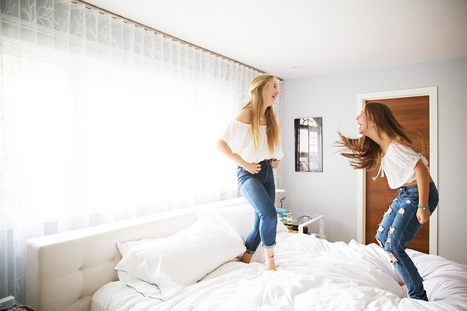 Teenaged sisters jumping on the bed