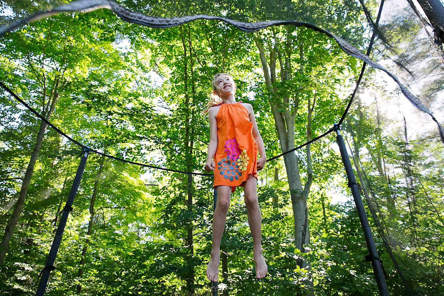 Girl jumping on a trampoline amongst the treest