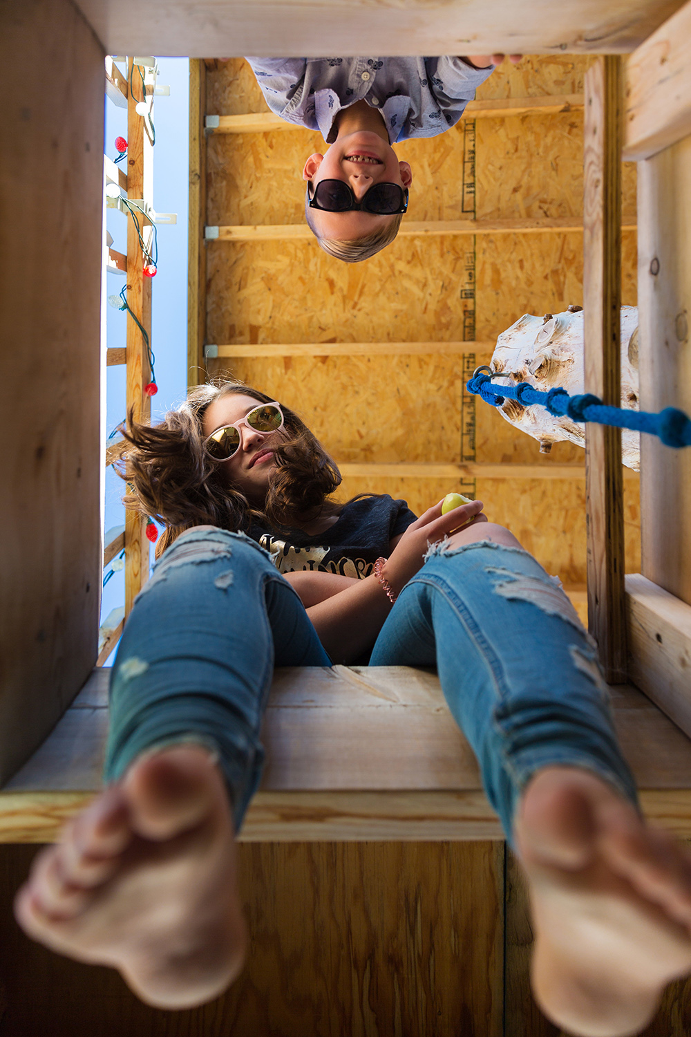 siblings looking down from their treehouse