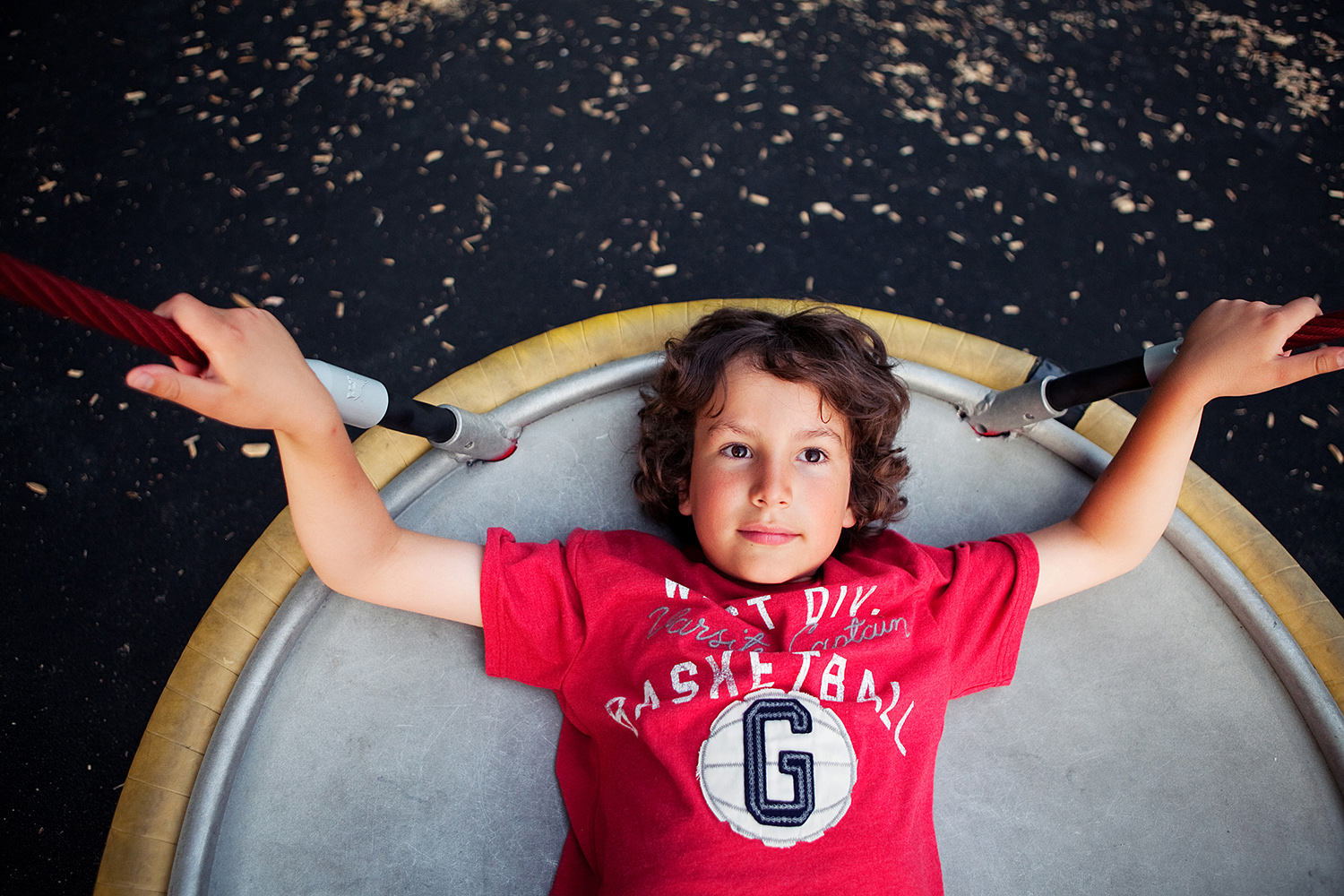 Boy with curly hair on a playground saucer