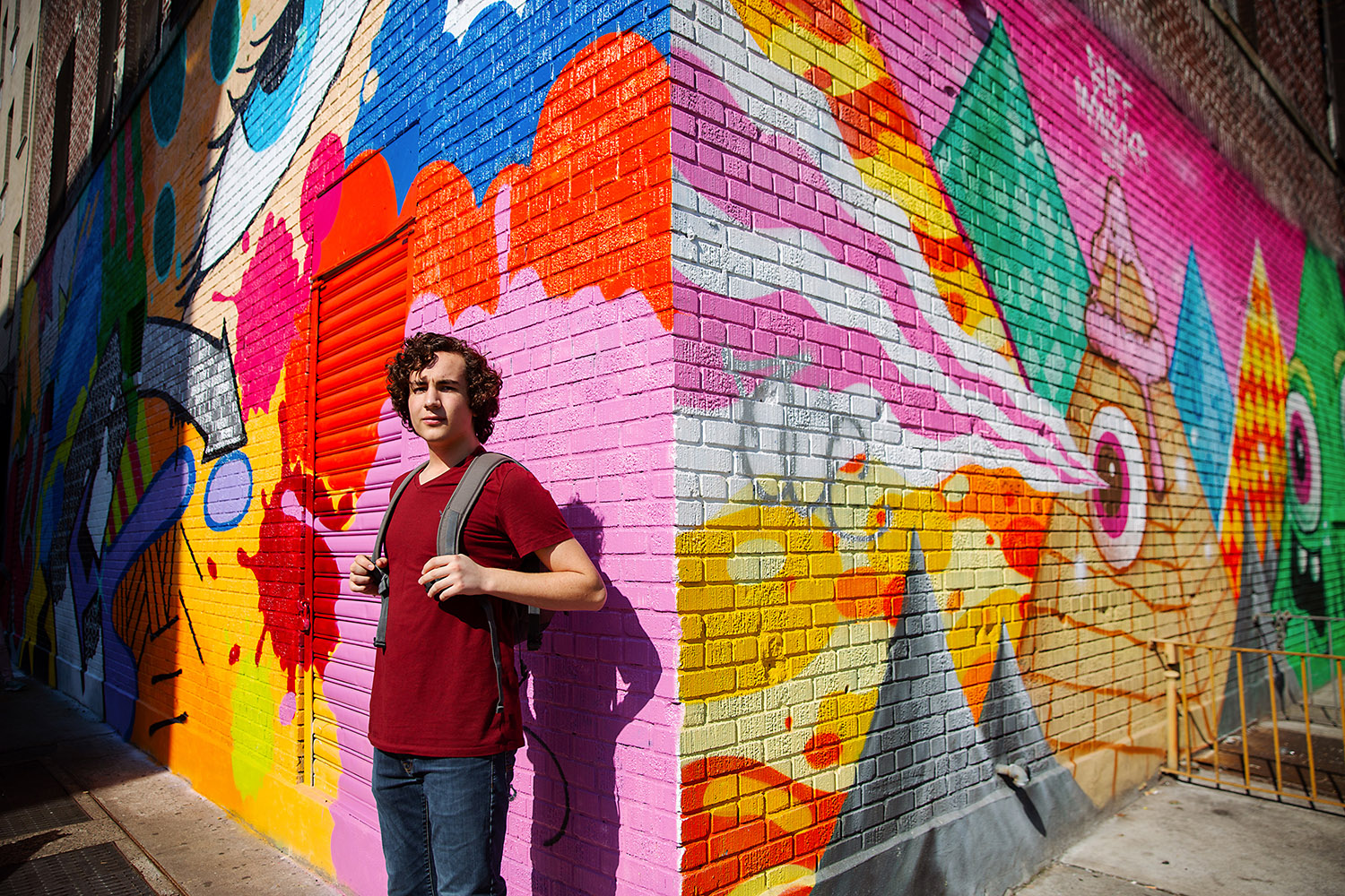 Teenaged boy in front of a graffiti mural in NYC