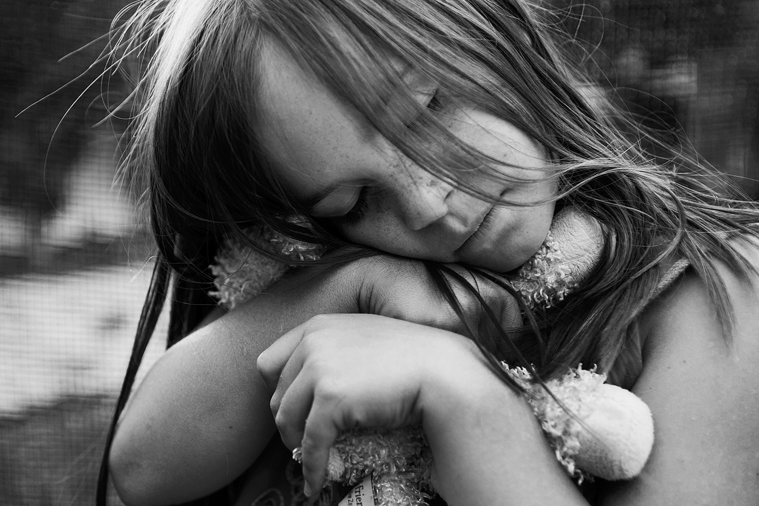 Black and white photograph of a girl hugging her stuffed animal