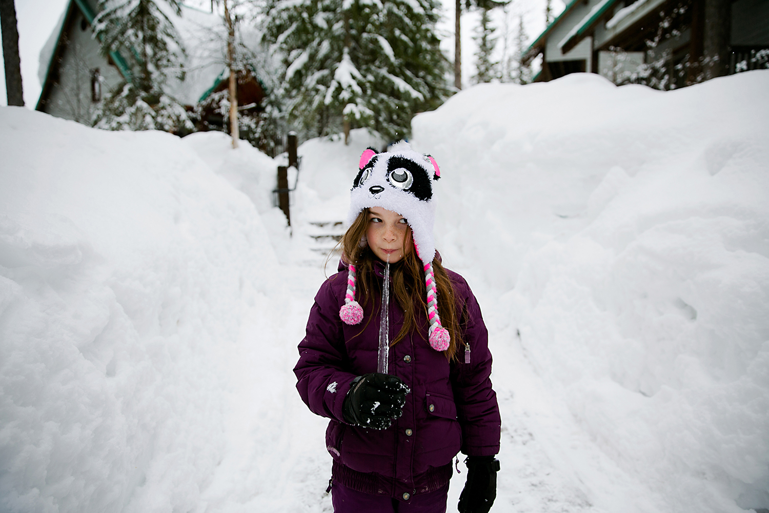Girl in deep snow eating an icicle at Emerald Lake Lodge