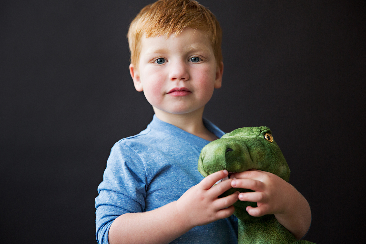 Studio portrait of a child holding stuffed dinosaur